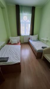 two twin beds in a room with a window at MAMRE Szálló in Hajdúböszörmény