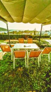 a table and chairs sitting under an umbrella on the grass at Villa Infinity View Athens Riviera in Anavyssos