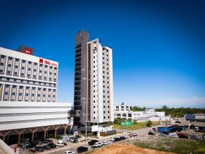 a tall white building with cars parked in a parking lot at Studio Completo Perto Hospital e Shopping in Tubarão