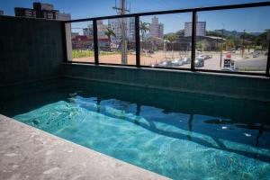a swimming pool with blue water in a building at Studio Completo Perto Hospital e Shopping in Tubarão