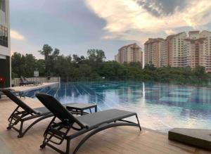 a swimming pool with two chairs and some buildings at ResidenShals in Putrajaya