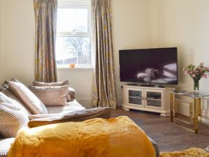 a living room with a couch and a flat screen tv at The Hind House in Cowlam