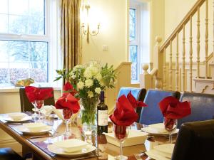 a table with red flowers and a bottle of wine at The Hind House in Cowlam