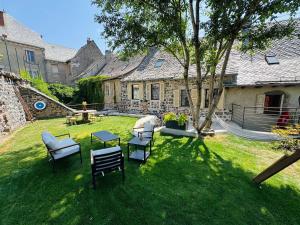 a yard with chairs and a hammock in front of a house at L'Echappée Belle in Laguiole