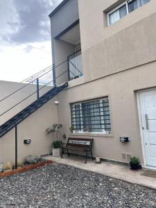 a bench sitting next to a building with a staircase at Apart Los Laureles Dpto 2 in Villa Regina