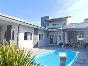 a villa with a swimming pool in front of a house at Casa com piscina Itapoá Itapema do Norte in Itapoa