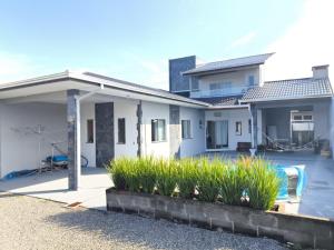 a white house with some plants in front of it at Casa com piscina Itapoá Itapema do Norte in Itapoa
