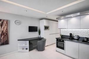 a kitchen with white cabinets and a black counter top at N9 Studentski Loft - Cozy Apt with Private Parking in Sofia