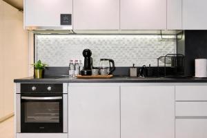 a kitchen with white cabinets and a black oven at N9 Studentski Loft - Cozy Apt with Private Parking in Sofia