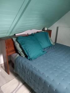 a bed with green pillows on it in a room at La maison de Yo in La Feuillée