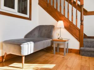 a chair in a living room with a table and stairs at Wesley Old Hall House in Bacup