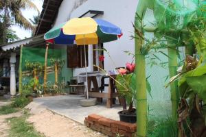 a patio with a table and an umbrella at Colonial Surfing Villa Hostel & Home Stay in Midigama East