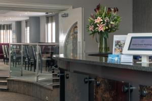 a lobby with a counter with a vase of flowers at Best Western The Plough Hotel in Northampton
