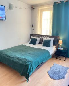 a bedroom with a large bed with a green blanket at Apartamenty przy Starówce in Olsztyn