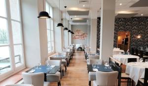 a dining room with white tables and white chairs at Le Moulin de Moissac, Sure Hotel Collection by Best Western in Moissac