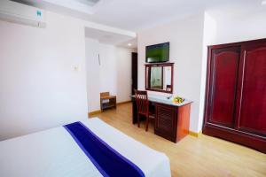 a bedroom with a bed and a desk and a television at Violet hotel&spa in Nha Trang