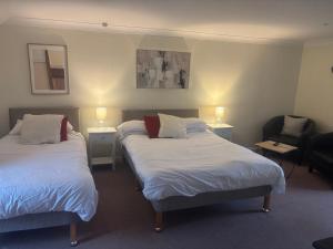 a bedroom with two beds and a chair and two lamps at Airds Farm Guest House in Castle Douglas