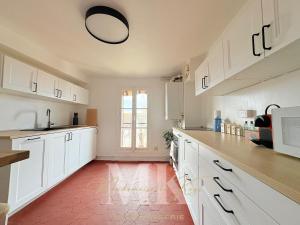 a kitchen with white cabinets and a red tile floor at L'Authentic - Appartement spacieux in Villeneuve-sur-Yonne