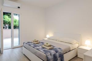 a white bedroom with a bed and a sliding glass door at Borgo Del Navigatore in Marina di Grosseto