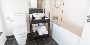 a bathroom with a sink and a toilet and a tub at Cape Cornwall Club in St. Just