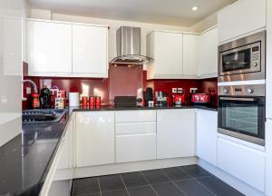 a white kitchen with white cabinets and appliances at Cranberry House Stylish 3BR, 7 Guests Contractor with Cinema Room Near JLR NEC and Airport in Sheldon