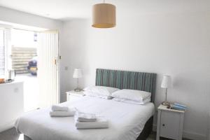 a bedroom with a white bed with towels on it at Cape Cornwall Club in St. Just