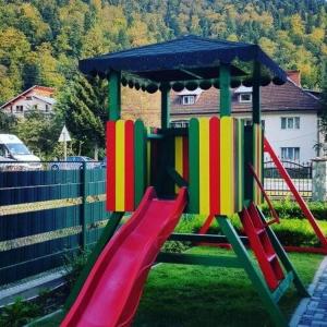 a playground with a colorful slide in a yard at White Wood Chalet in Buşteni