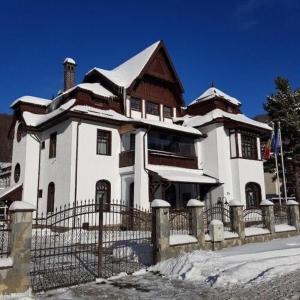 a large house with a fence in front of it at White Wood Chalet in Buşteni