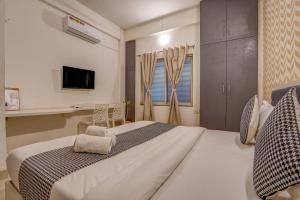a bedroom with a large white bed and a tv at Urban Villa ,Baner in Pune