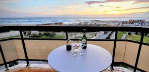 a table with wine glasses on a balcony with a view of the beach at JES holidays in Costa da Caparica