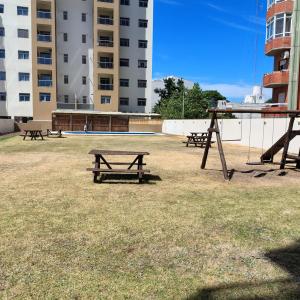 a group of picnic tables in a field with buildings at Los corales torre norte in Santa Teresita
