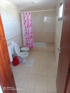 a bathroom with a toilet and a pink shower curtain at Los corales torre norte in Santa Teresita +3 photos