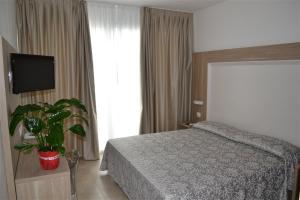 a bedroom with a bed and a flat screen tv at Fruit Village Torre dell'Orso La Brunese 4stelle in Torre dell'Orso +21 photos
