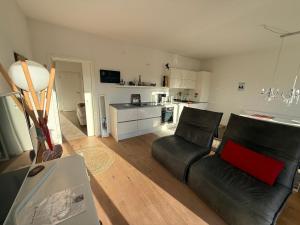 a living room with a black couch and a kitchen at Ferienwohnung Burgenblick mit Blick auf Riedenburg in Riedenburg