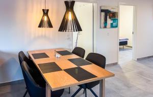 a dining room table with black chairs and lights at Awesome Home In Ringkøbing With Wifi in Ringkøbing