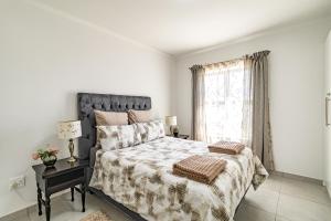 a white bedroom with a large bed and a window at Cozy Cove St Helena in West Point