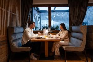 a man and woman sitting at a table in a restaurant at Tevini Dolomites Charming Hotel in Commezzadura