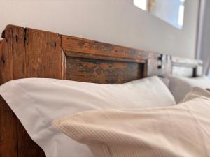 ein Bett mit weißen Laken und einem hölzernen Kopfteil in der Unterkunft Capitolium Ad in Brescia