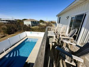 a swimming pool with chairs next to a house at KD1730 - Cole's Cabana in Kill Devil Hills