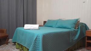 a bed with a blue comforter with a towel on it at Iguazú Cabañas in Puerto Iguazú