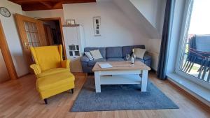 a living room with a couch and a table and a yellow chair at Residenz am Deich NDD 28 in Norden
