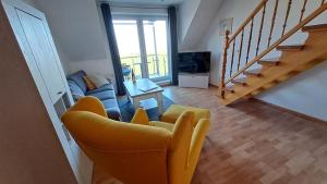 a living room with a yellow chair and a couch at Residenz am Deich NDD 28 in Norden