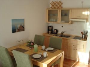 a kitchen with a wooden table with green chairs at Küstenliebe in Kirchdorf