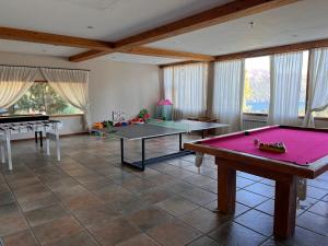 a living room with two ping pong tables and windows at Estancia Del Carmen Mountain Resort in San Carlos de Bariloche