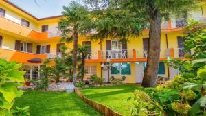 an orange and white building with a yard at Hotel Al Pescador in Lazise
