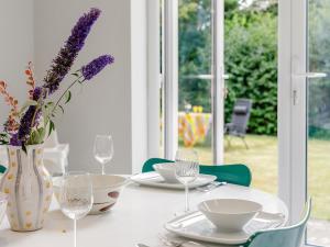 a table with plates and glasses and a vase with purple flowers at 4 Bed in Mablethorpe oc-77958 in Sutton on Sea +16 photos