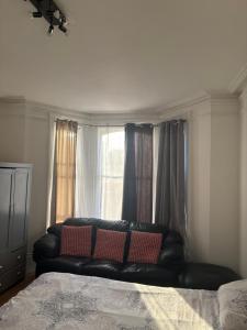 a black leather couch sitting in front of a window at Crystal in Crystal Palace +4 photos