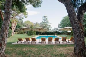 a group of chairs and umbrellas next to a pool at Masia Can Pares in Sant Pere de Ribes