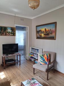 a living room with a tv and a couch and a chair at Stop-a-While in Krugersdorp