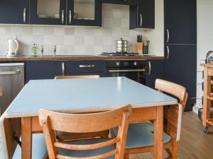 a kitchen with a blue table and chairs at Eastcliff Bungalow in Mundesley